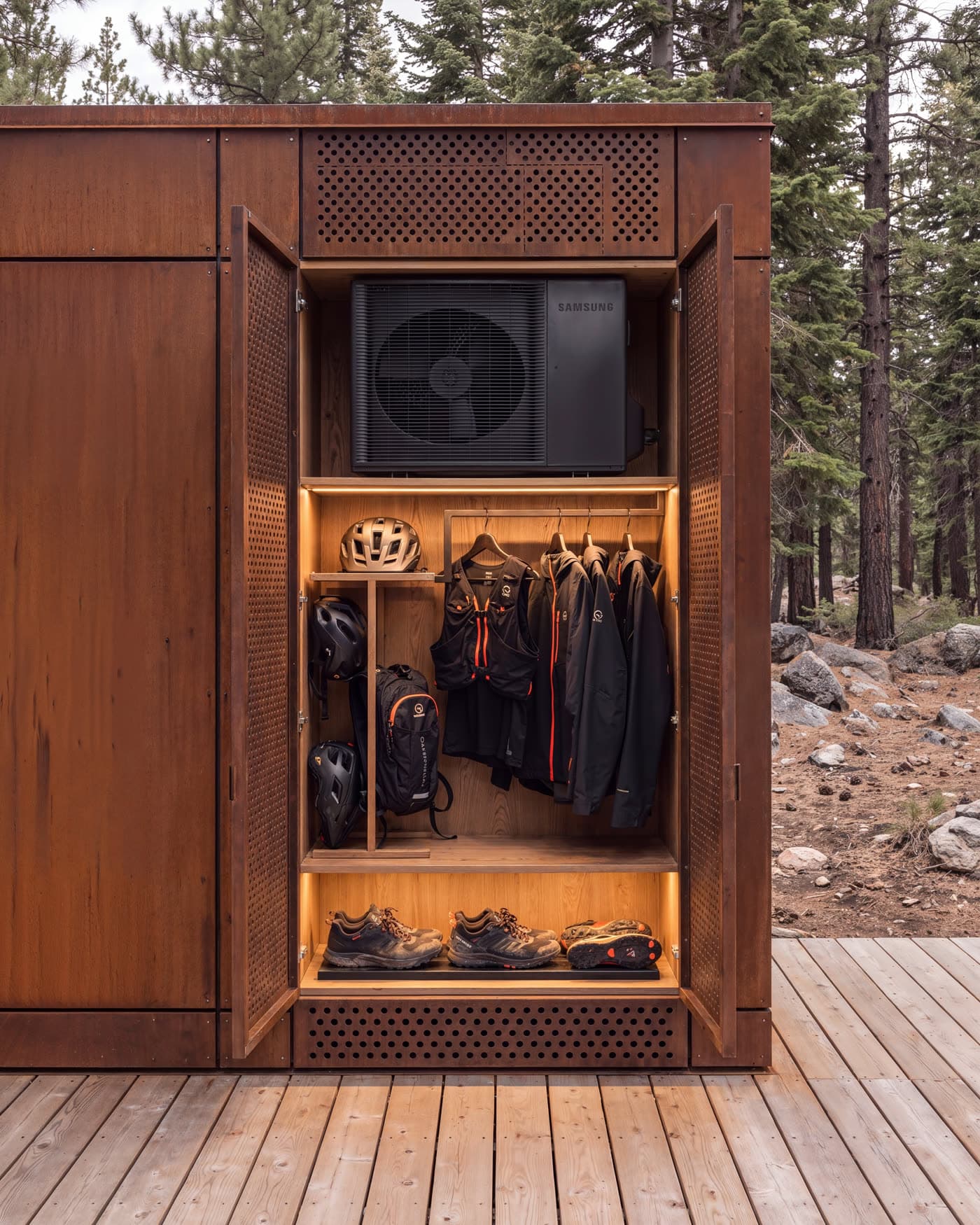 A corten gear locker open on the deck, holding a helmet, pack, jackets and trail shoes